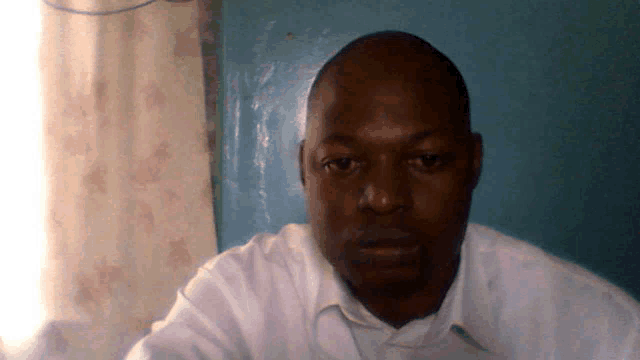 a man wearing a white shirt looks at the camera