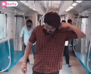 a man wearing headphones is dancing on a subway train .