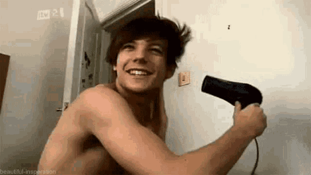 a shirtless man is holding a hair dryer in his hand .