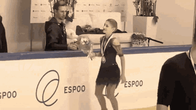 a female figure skater is holding a bouquet of flowers while wearing a medal