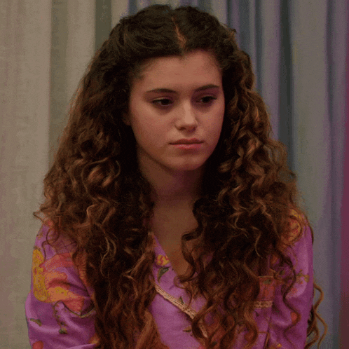 a woman with curly hair is wearing a purple pajama top