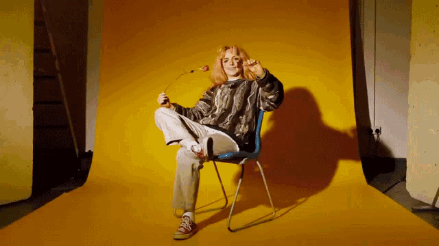 a woman sitting in a chair holding a flower