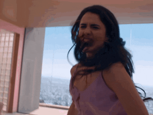 a woman in a purple tank top is making a funny face