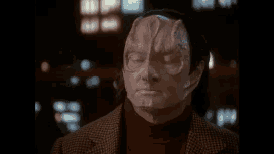 a man with a mask on his face is looking at the camera .