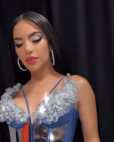 a woman wearing a blue and silver dress has a tattoo on her shoulder that says " desire "