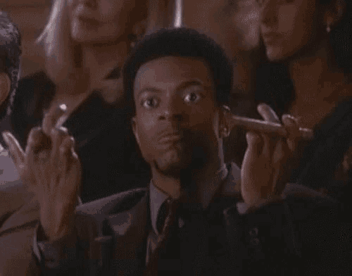 a man in a suit and tie is giving the middle finger in a crowd of people .