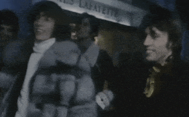 a woman in a fur coat is walking with a man in a yellow tie