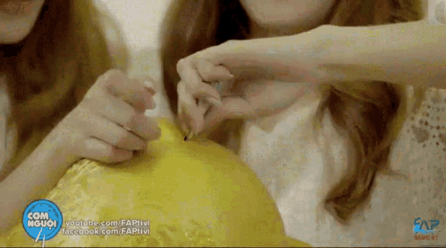 two girls are playing with a yellow ball with a facebook logo in the upper right corner