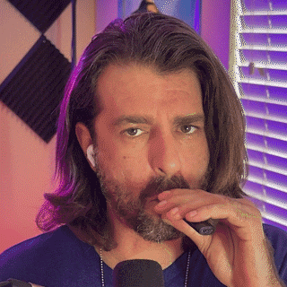 a man with long hair and a beard is smoking a cigarette