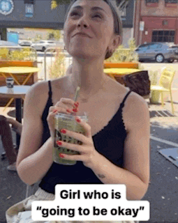 a woman is drinking a green smoothie with a straw while sitting at a table .
