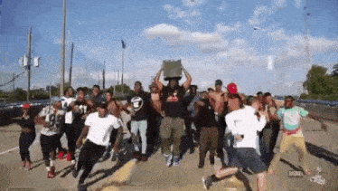 a group of people are dancing on a street and one of them is holding a sign that says ' a ' on it