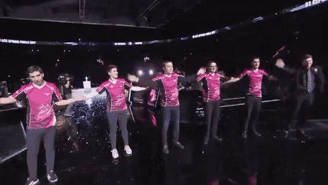 a group of people in pink shirts are dancing on a stage in a dark room .
