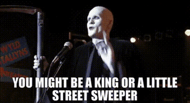 a bald man is standing in front of a microphone and a sign that says wild stallion .