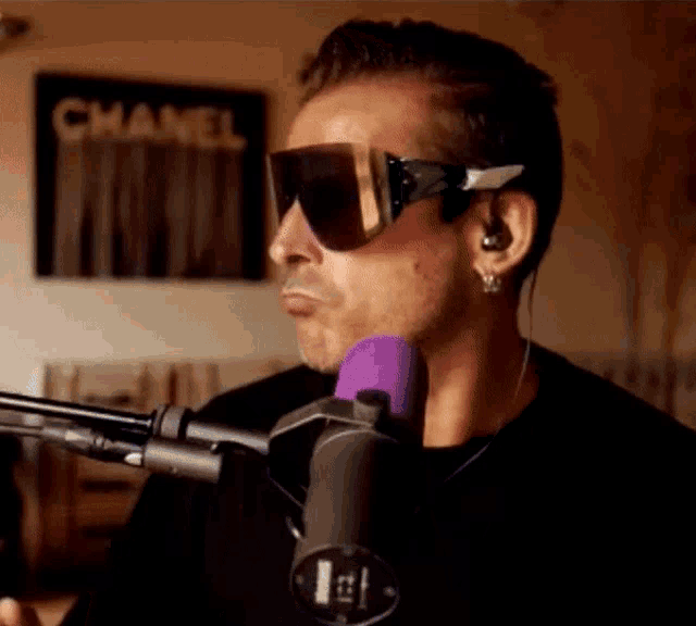 a man wearing sunglasses is singing into a microphone