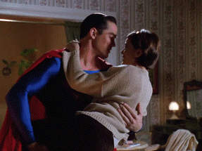 superman is holding a woman in his arms in a bedroom