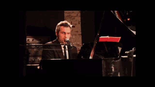 a man singing into a microphone at a piano