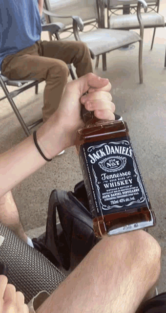 a person is holding a bottle of jack daniel 's