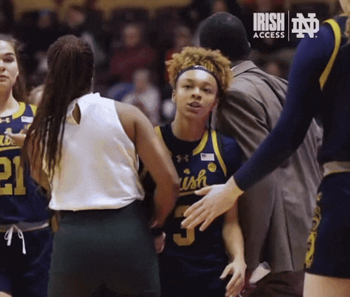 a basketball player wearing a number 5 jersey talks to another player