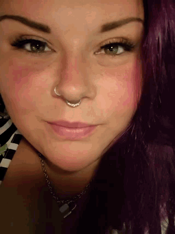 a woman with purple hair has a nose ring in her nose