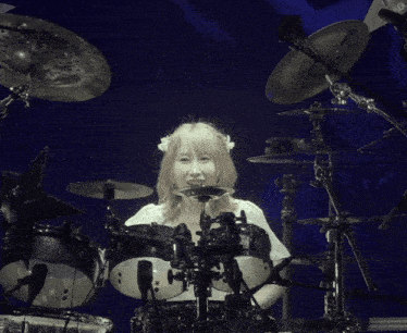 a woman in a white dress is playing a drum set