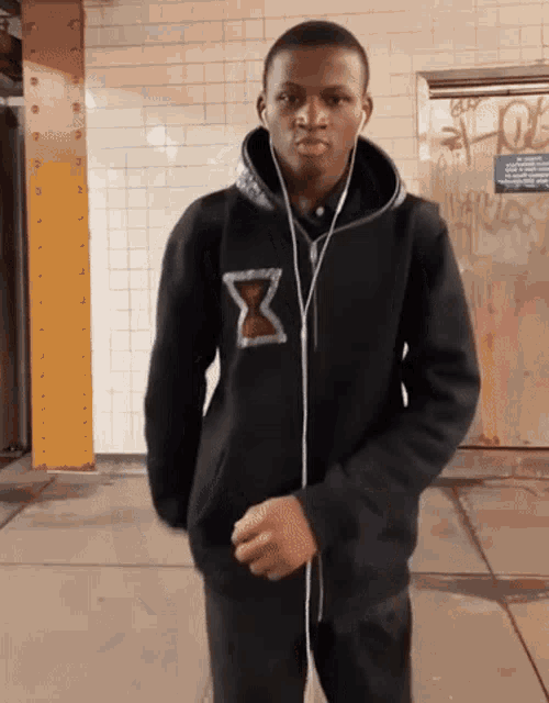a man wearing headphones and a black hoodie with a hourglass on it