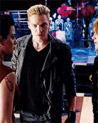 a man and two women are standing next to each other in a dark room .