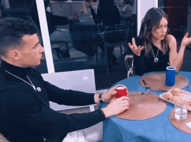a man in a black turtleneck sits at a table with a woman in a black top