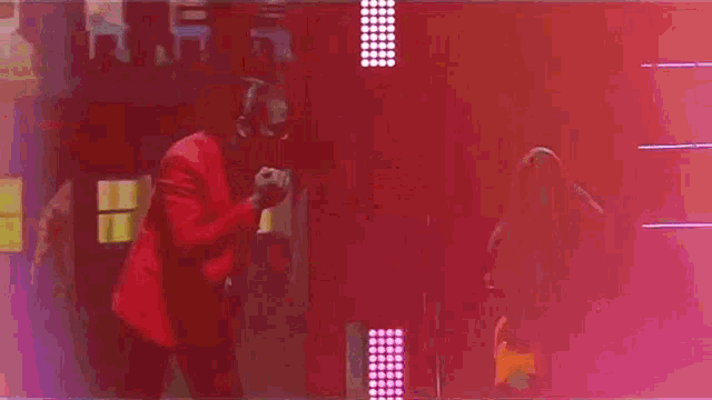 a woman in an orange dress is dancing on a stage with a man in a red shirt behind her .