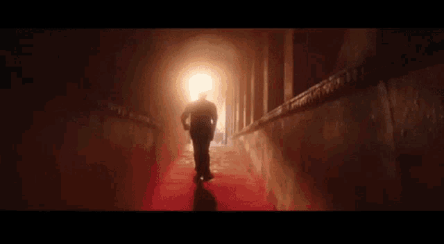 a man is walking down a hallway with lightning coming down the walls .