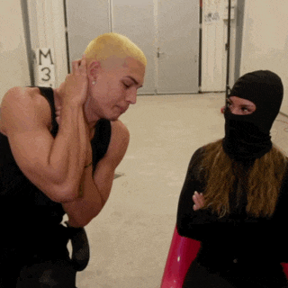 a man in a black tank top and a woman in a black mask are standing in front of a door that says m3