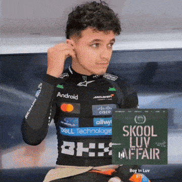 a man adjusts his ear buds next to a sign that says " skool luv affair "