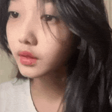 a close up of a girl 's face with long black hair and red lipstick .