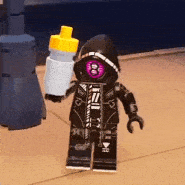 a lego figure is holding a bottle of water in his hand .