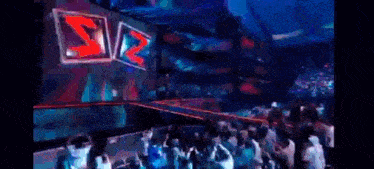 a crowd of people are dancing in front of a stage with a large z on it .