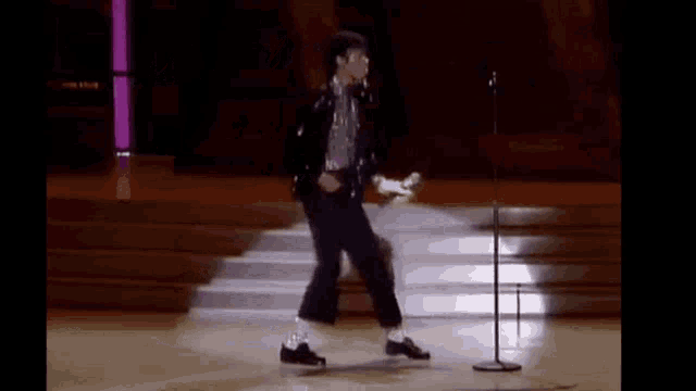 michael jackson is walking on a stage in front of a microphone .