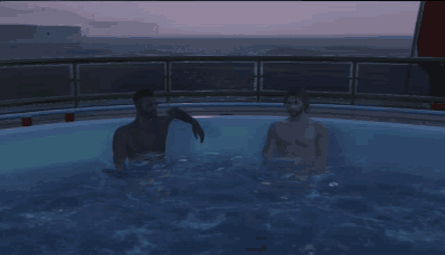 two naked men are sitting in a hot tub