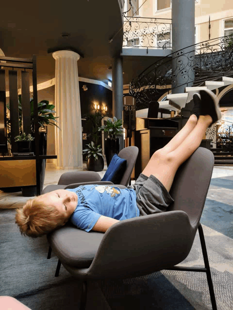 a boy laying on a chair with his legs up