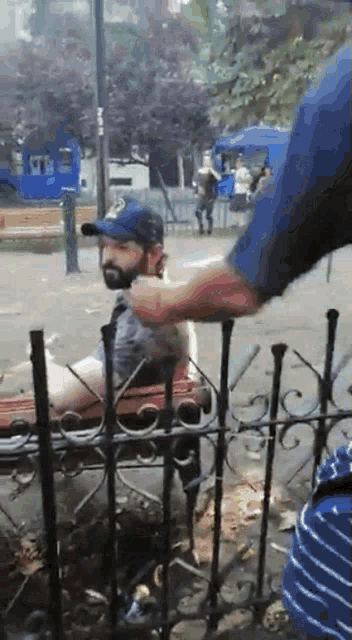 a man with a beard is sitting on a bench in a park