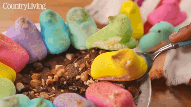 a spoon is being used to scoop peeps out of a bowl of chocolate