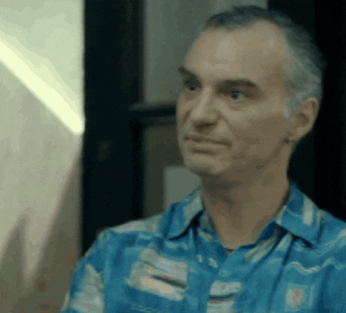 a man wearing a blue shirt with a hawaiian pattern