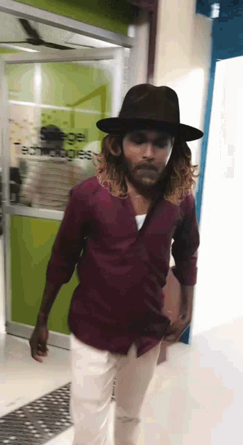 a man with long hair and a hat walks in front of a door that says actions