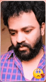 a man with a beard is wearing a plaid shirt and has a sad smiley face next to him