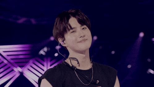 a man wearing a black shirt and ear buds is dancing on a stage