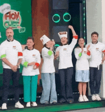 a group of chefs are standing on a stage in front of a green background .