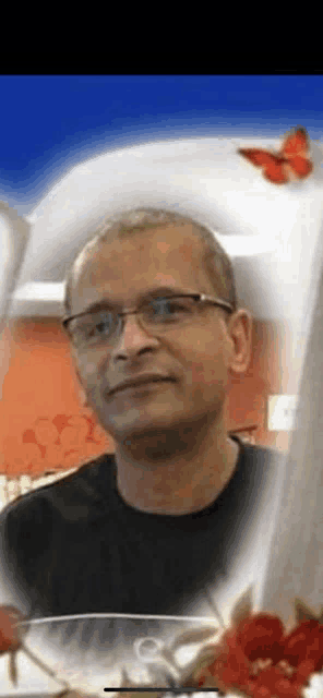 a man wearing glasses and a black shirt is standing in front of a vase of red flowers .