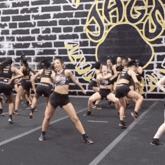 a group of cheerleaders are performing in front of a brick wall with the word high on it