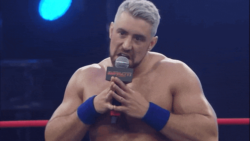 a man in a wrestling ring holds a microphone that says impact on it