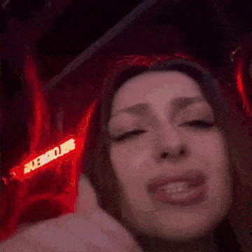 a close up of a woman 's face in front of a red sign that says aexv
