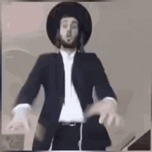 a man in a suit and hat is dancing with his arms outstretched .