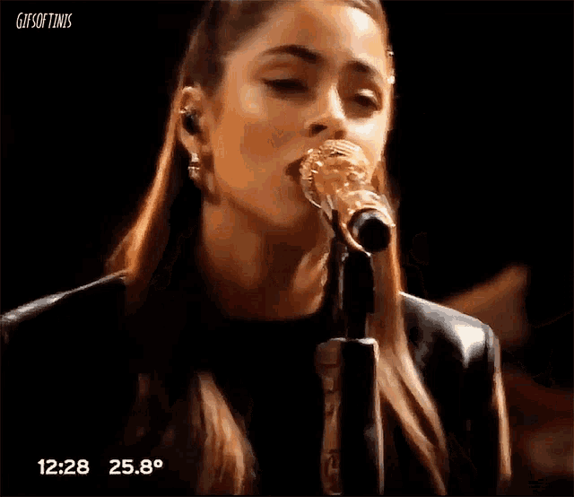 a woman singing into a microphone with the time 12:28